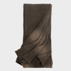 Brown chunky knit blanket folded and draped showcasing its textured weave