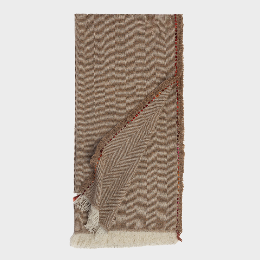 Rg159mth | Amity Home Beige herringbone throw blanket with fringed edges folded to reveal a red stitched border and tassels at the corner