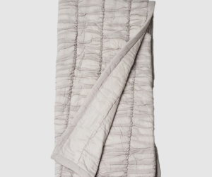 Light gray quilted blanket folded with vertical channel stitching visible throughout