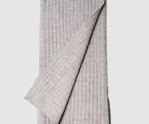 Light gray textured blanket folded with one corner pulled over