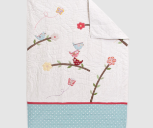 Decorative quilt with pastel birds on branches colorful flowers and a blue polka dot border on a white background