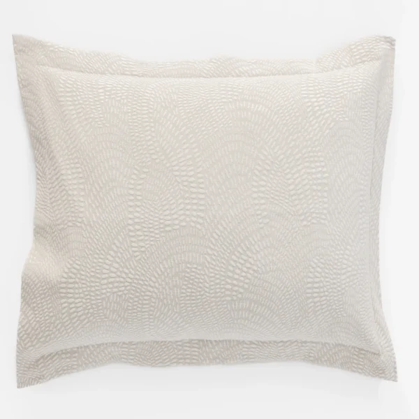 Beige decorative throw pillow with a textured dotted pattern on a white background viewed from the side edges clearly showing the fabric texture