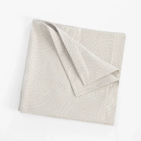 Light beige folded fabric with a subtle raised geometric pattern on a white background