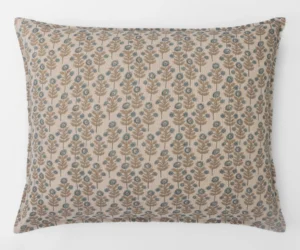 Decorative beige pillow with blue floral pattern against a white background