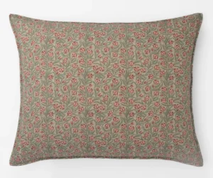 Patterned decorative pillow with pink flowers and green leaves on a beige background