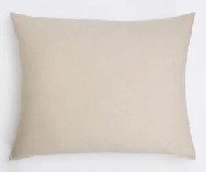 Beige textured throw pillow resting on a white surface plain and minimalist look