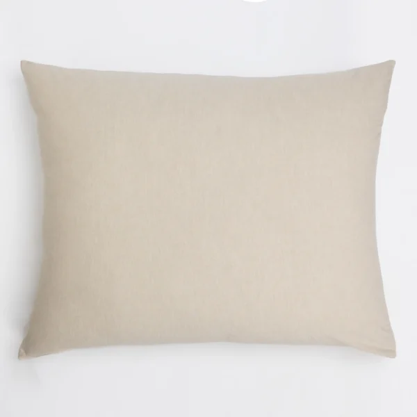 Beige textured throw pillow resting on a white surface, plain and minimalist look