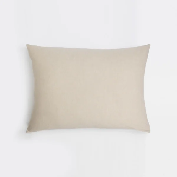Beige linen pillow resting on a white background seen from a slight angle
