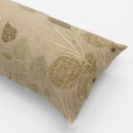Beige fabric pillow with a green botanical leaf pattern on a white background close up view