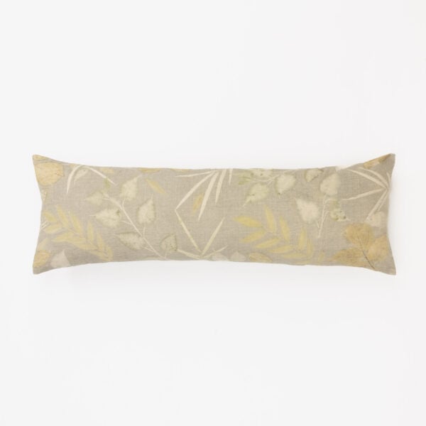 Partial view of a decorative pillow with a pale botanical leaf pattern along the bottom edge on a white background.