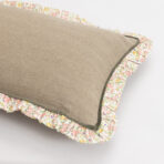 Close up of stacked burlap front cushions with floral printed ruffled edges showing pink yellow and green floral pattern