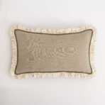 Beige fabric cushion with a floral ruffle trim against a white background