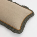 Beige burlap cushion with brown piping resting on a dark green plaid pillow
