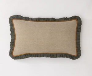 Beige throw pillow with brown edging and a dark green plaid ruffle border on a white background