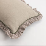 Stack of beige textured pillows with green edging resting on a brown and white checkered fabric against a light background