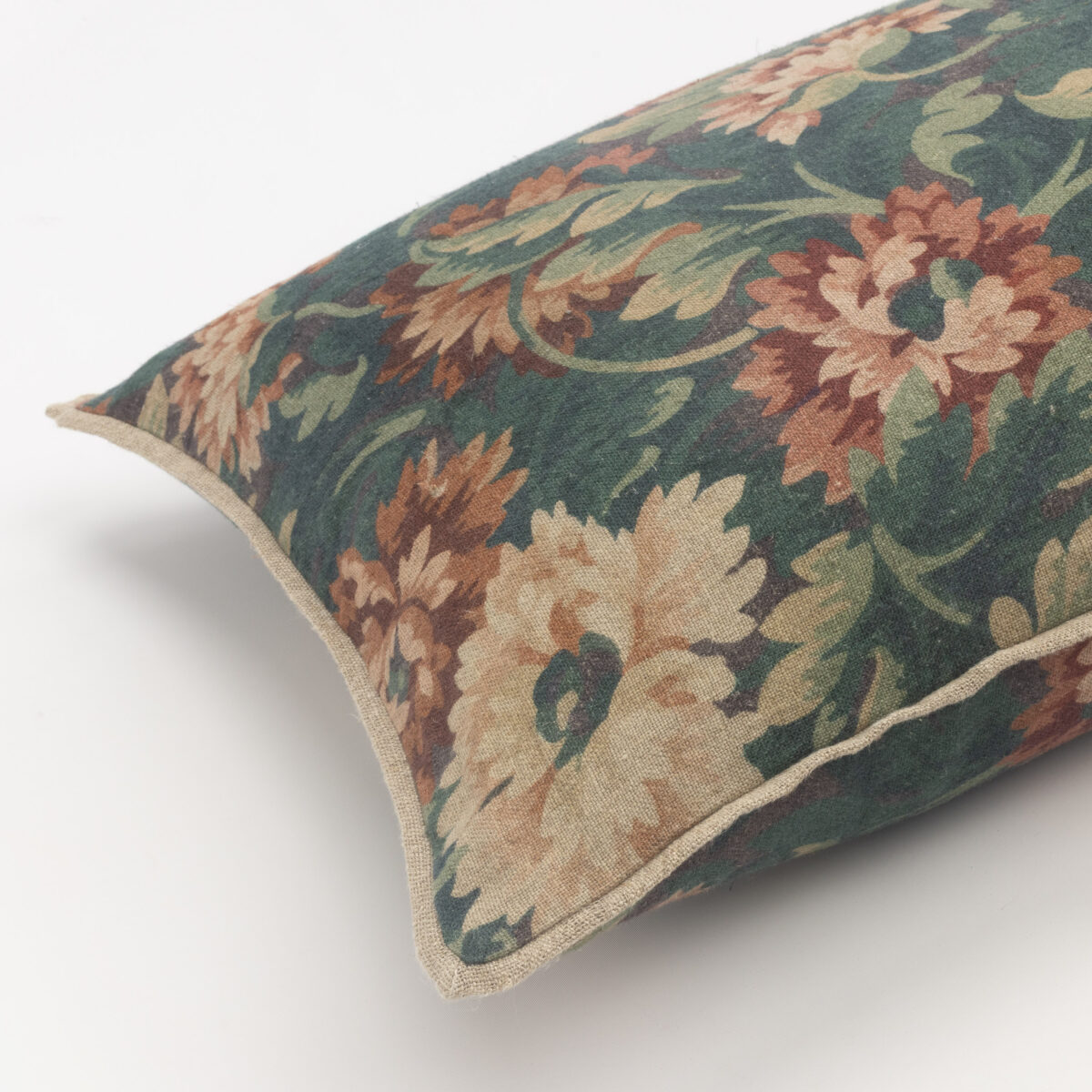 Close up of a decorative pillow with a vintage floral tapestry pattern in green brown and cream tones