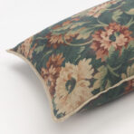 Close up of a decorative pillow with a vintage floral tapestry pattern in green brown and cream tones