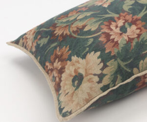 Close up of a decorative pillow with a vintage floral tapestry pattern in green brown and cream tones
