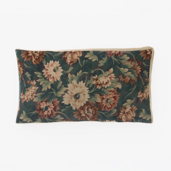 Decorative throw pillow with dark green fabric and large pinkish-brown floral print, beige trim. (informative)