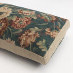 Close up of a decorative cushion with a dark floral tapestry pattern on beige fabric