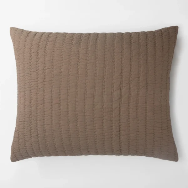 Close up of a brown quilted pillow with vertical rows of stitching on a white background
