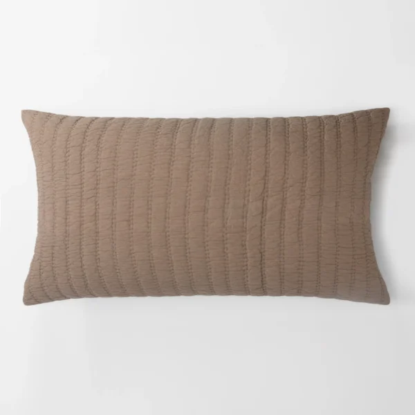 Partial view of a brown quilted cushion against a white background