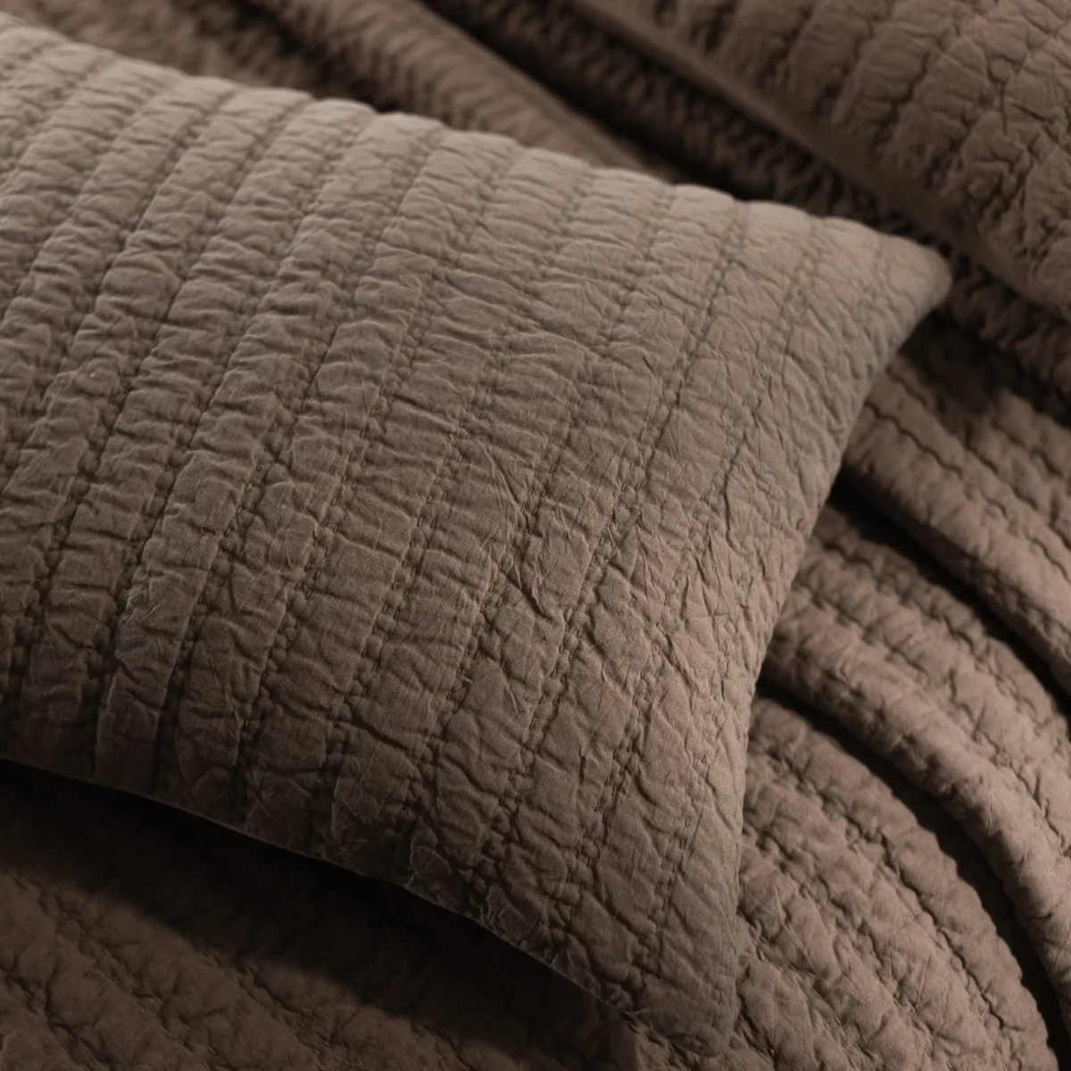 Close up of quilted fabric with diagonal diamond stitching in gray tones