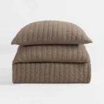 Stack of two taupe quilted pillows with a textured stitched pattern against a light background