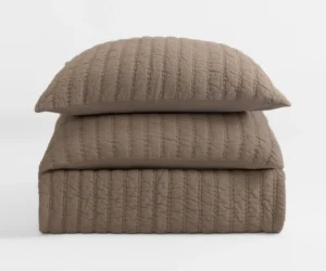 Stack of two taupe quilted pillows with a textured stitched pattern against a light background