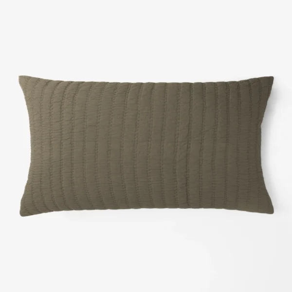 Close up of a brown quilted pillow edge on a white background
