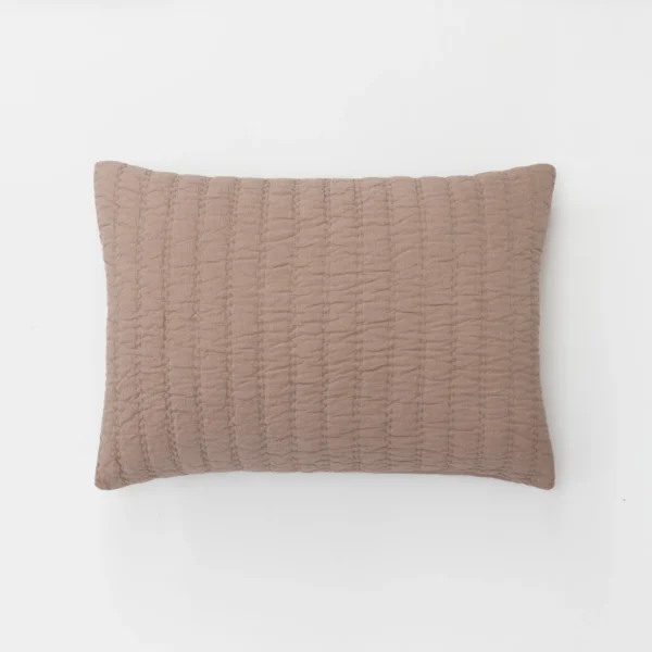 Dusty pink quilted pillow partially shown against a white background edge visible at bottom of frame
