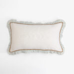 Decorative beige pillow with blue striped ruffle edge and brown trim on a white background close up view