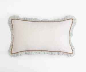 Decorative beige pillow with blue striped ruffle edge and brown trim on a white background close up view