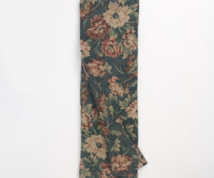 Folded length of dark green floral fabric with tan and dusty rose flowers viewed from above showing a textile swatch
