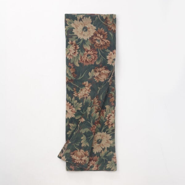 Folded length of dark green floral fabric with tan and dusty rose flowers, viewed from above, showing a textile swatch.
