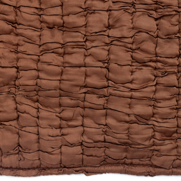 Close up of brown quilted fabric with rectangular padded sections and visible stitching in a grid pattern