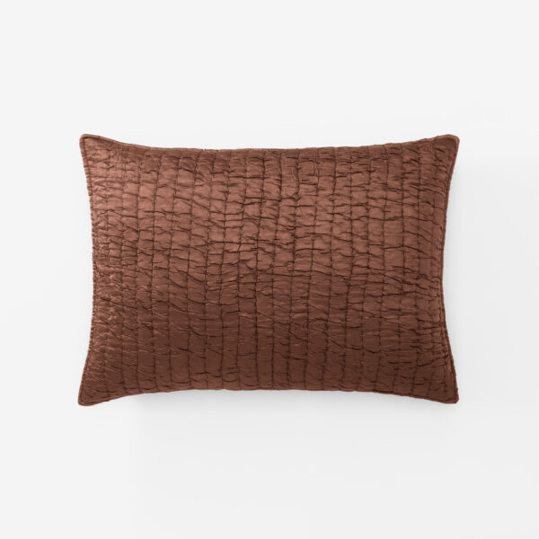 Brown quilted pillow with a grid like stitched pattern on a white background