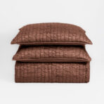 Stack of brown quilted cushions stacked on a white background showing a textured grid pattern on the fabric
