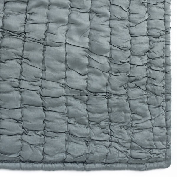 Close up of grey quilted fabric with square stitched panels and puffy padding