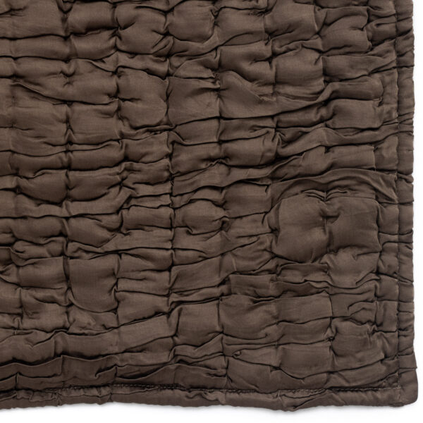 Close up of dark brown quilted fabric with irregular pillowed channels and soft texture