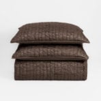Stack of brown quilted pillows stacked on a white background to the center of the image