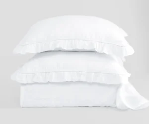 Stack of white pillows neatly stacked on a light grey background showcasing a soft bedding product