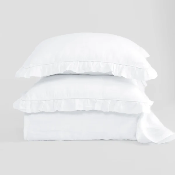Stack of white pillows neatly stacked on a light grey background, showcasing a soft bedding product.