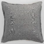 Gray woven fabric pillow with frayed edges on a light background close up view of texture and stitching