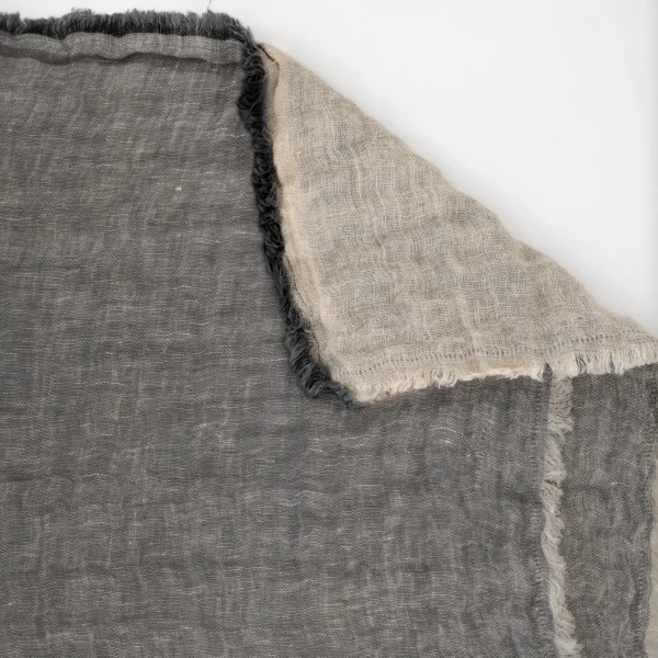 Close-up of two woven fabrics stacked together, gray on the left and beige on the right, with frayed edges visible.