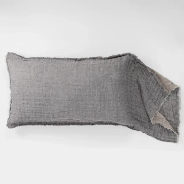 Gray frayed fabric swatch laid on a white surface showing rough edges and woven texture in neutral tones