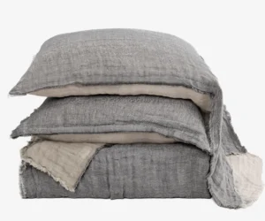 Stack of gray denim pillows with frayed edges stacked on a white background