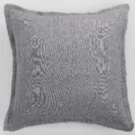 Grey textured linen cushion with frayed edges on a white background close up view