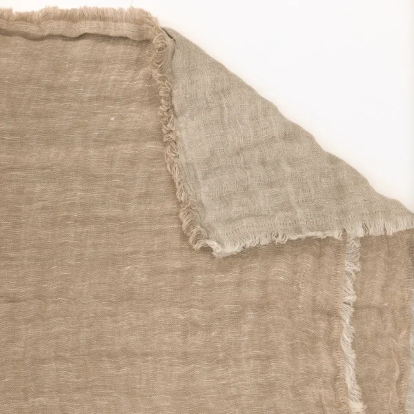 Close-up of beige burlap fabric with a frayed edge along a seam, highlighting the coarse woven texture.