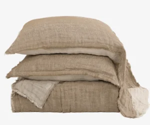 Stack of beige linen cushions with frayed edges against a white background